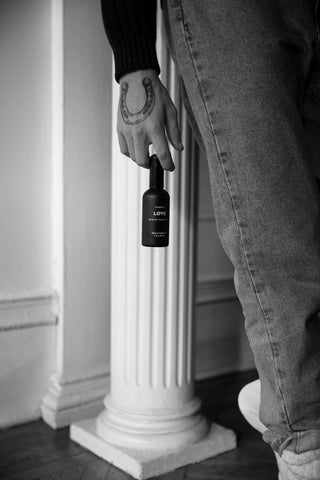 Person in denim holding LOVE aromatic concentrate in their hand. This concentrated room and linen spray is made from natural essential oils including jasmine and ylang ylang.