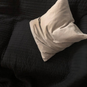 A crumpled pillow on black sofa.